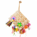 Colorful woven hanging parrot toy with natural palm leaf mat, tassels, bell, and chewable enrichment accessories on a white background.